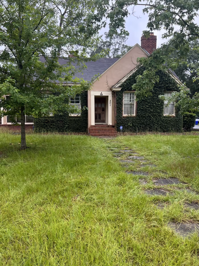 Ivy-covered brick cottage with overgrown yard purchased as-is in Georgia