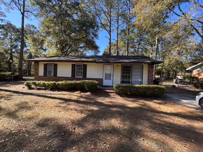 Yellow and brick ranch home with leaf-covered lawn bought in as-is condition